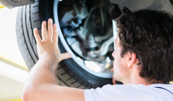 Mechanic working in car workshop on wheel